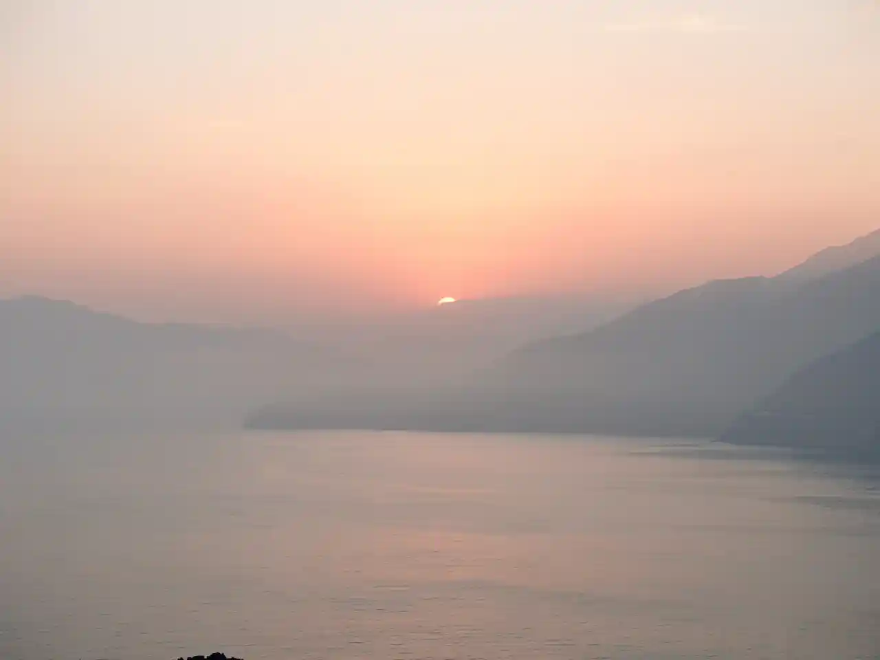 Serene sunrise over a calm sea or misty mountains, representing peace and God's presence