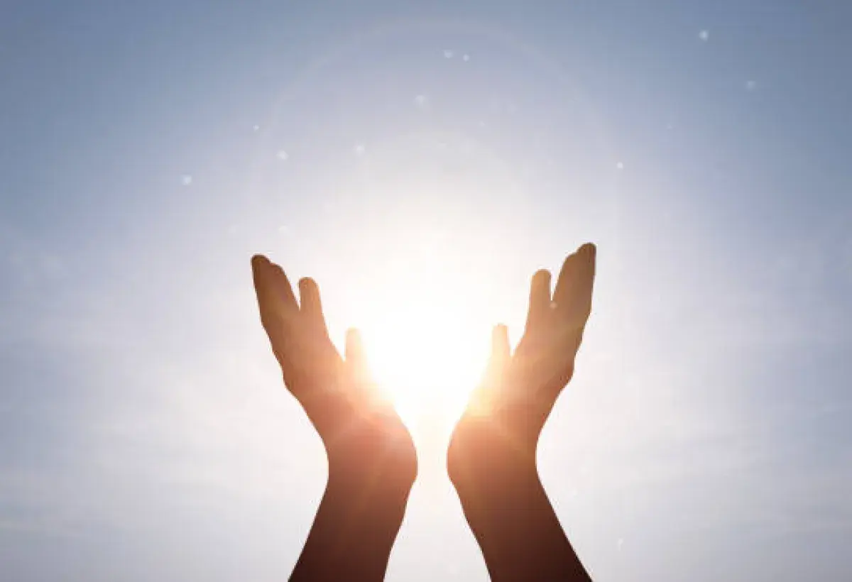 Hands lifted in faith toward the light, representing trust and renewal through God.