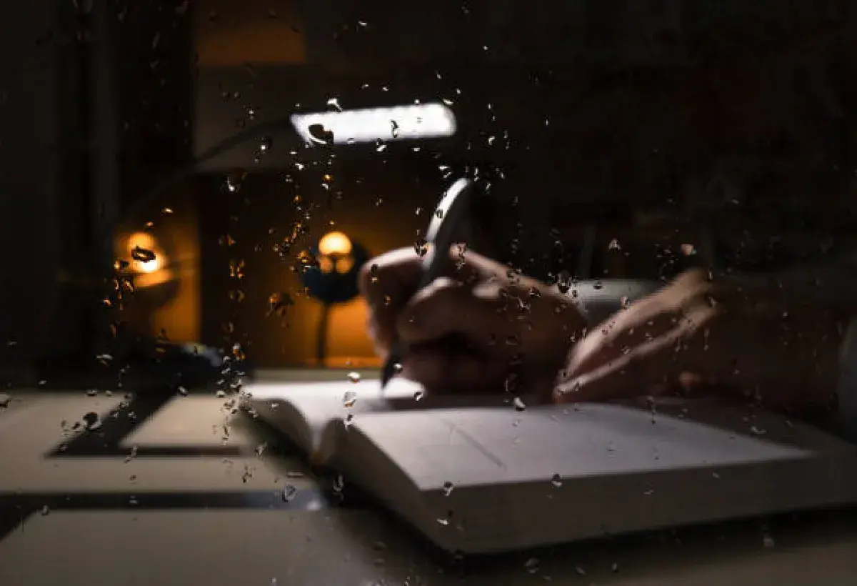 Writing beside a candle during a storm, symbolizing endurance and hope