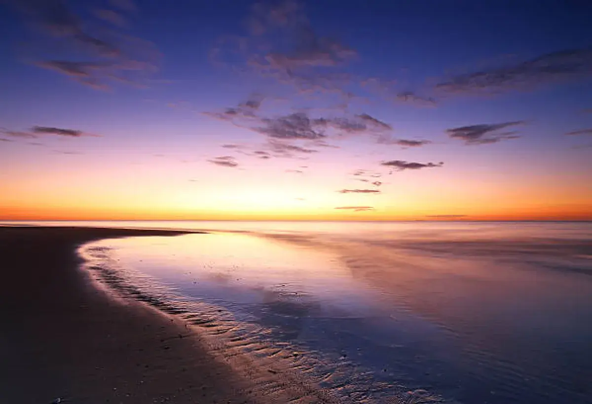 Sunset over a calm shoreline, symbolizing mental peace and acceptance