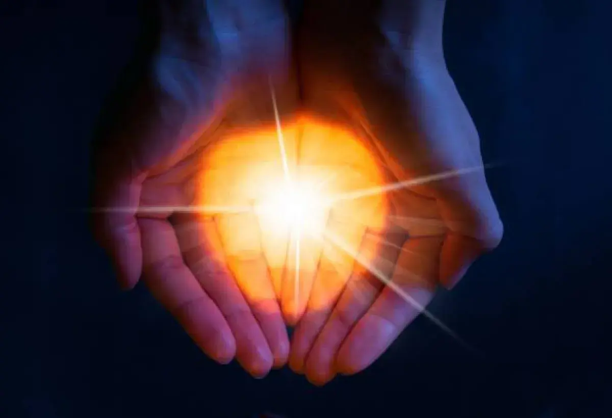 Hands holding light that represents the quiet power of joy.