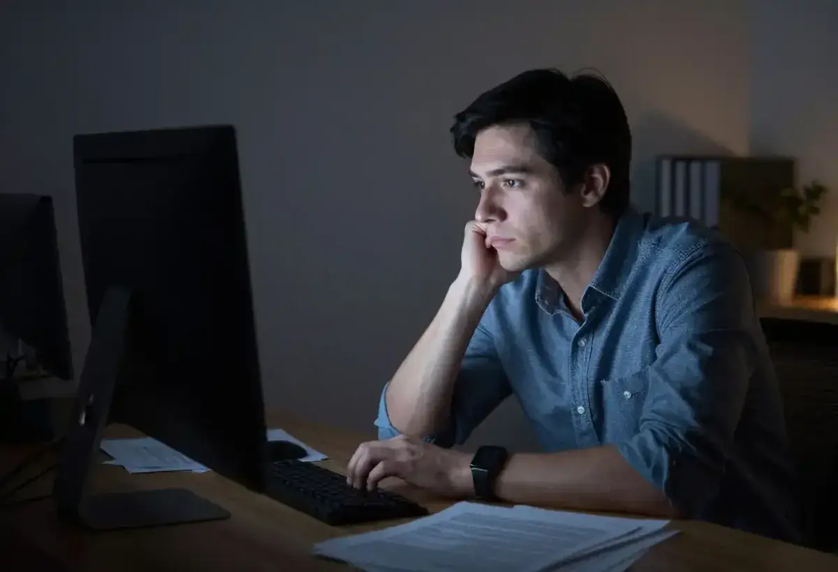Professional staring blankly at computer screen showing emotional detachment from work