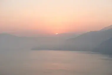 Serene sunrise over a calm sea or misty mountains, representing peace and God's presence